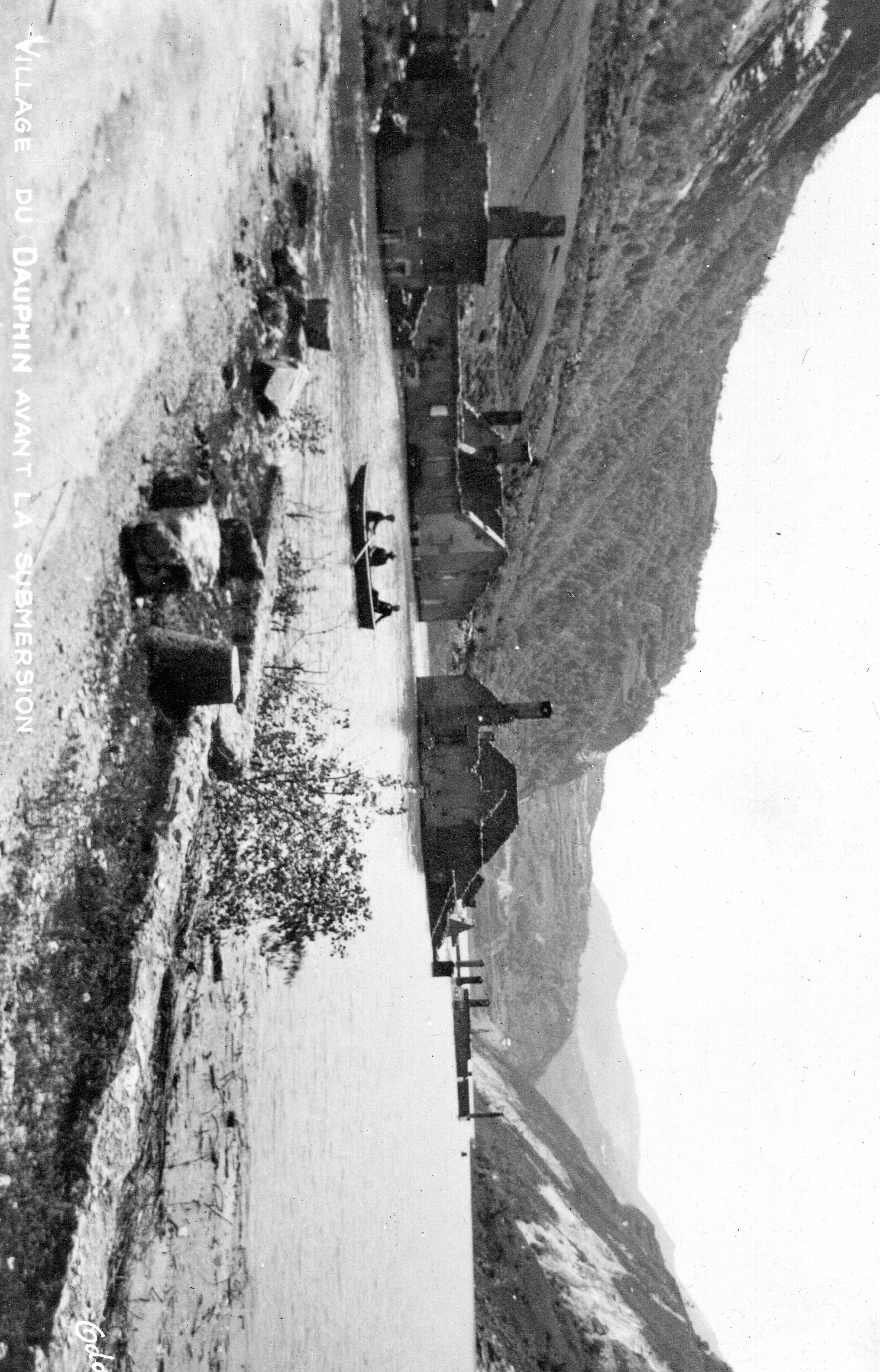 En 1935, trois hommes naviguent en barque parmi les maisons à moitié immergées du village du Dauphin, avant sa submersio