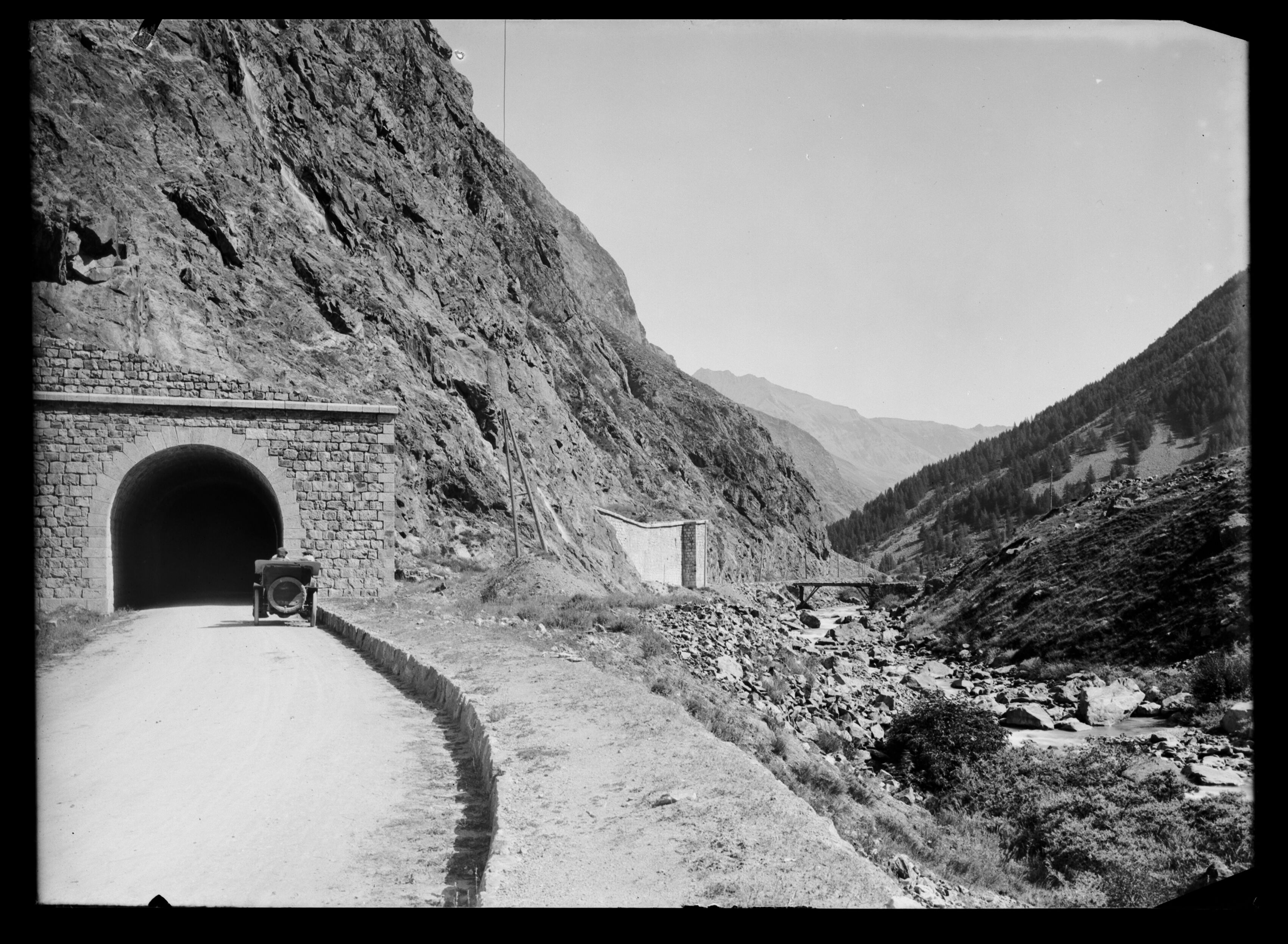 Une voiture entre dans le tunnel du Dauphin, avec un fragile pont sur la Romanche en arrière-plan. Cette image, prise au