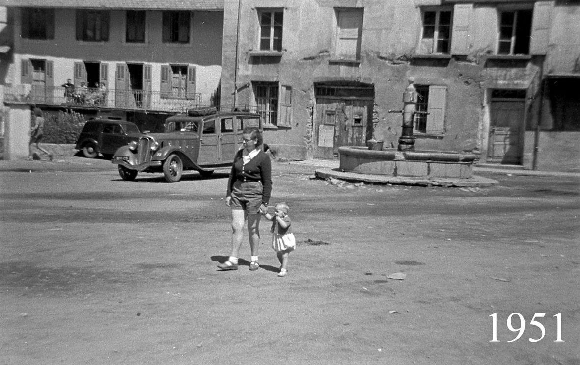 Mère et enfant, devant la fontaine et le Bec de l'Homme. En fond des anciennes automobiles et trois personnes assises su
